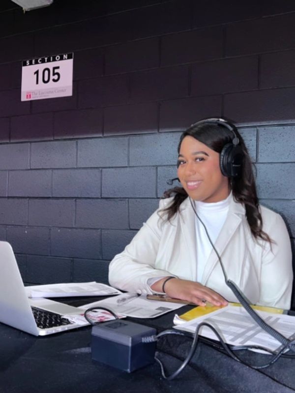 Woman in a headset working at a desk with laptop and papers.