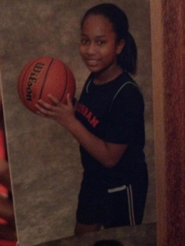 Young girl holding a basketball, smiling for a photo.