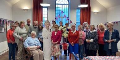 Group of older adults posing with a Queen Elizabeth II cutout.