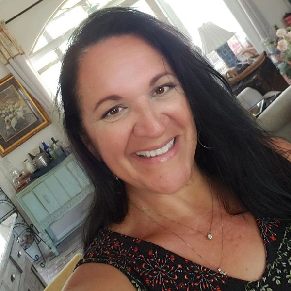 Smiling woman with long dark hair in a cozy room.
