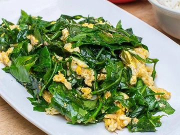 A plate of stir-fried leafy greens with scrambled eggs.