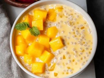 A bowl of mango sago dessert with fresh mango cubes and mint garnish.