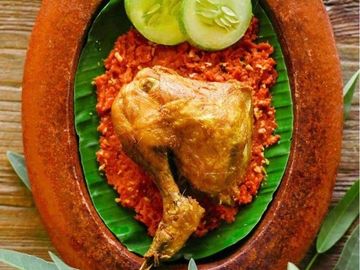 Fried chicken leg served on spicy red sauce with cucumber and basil garnish.