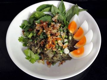 A dish with boiled eggs, fresh herbs, and a savory topping on a white plate.