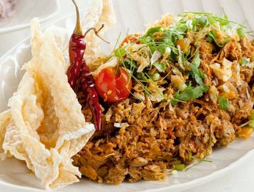 Thai spicy shredded chicken salad with crispy pork rinds and dried chilies.