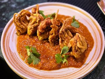 Crispy fried soft shell crabs served on a spicy red sauce with cilantro garnish.