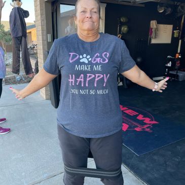 A woman wearing a humorous dog-themed shirt and exercising outdoors.