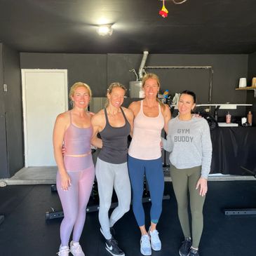 Four women in workout clothes posing in a gym.