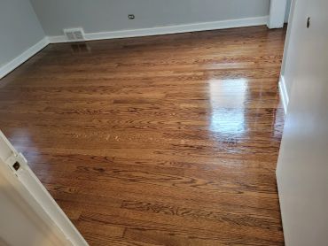 Polished hardwood floor in an empty room with white walls.