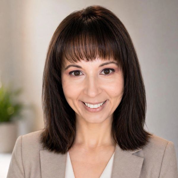 Professional woman with shoulder-length dark hair smiling in business attire.