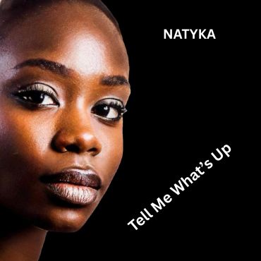 Close-up portrait of a woman with text 'NATYKA' and 'Tell Me What's Up'.