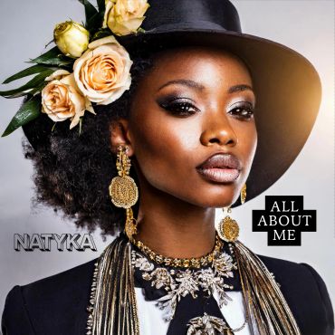 Elegant woman in a wide-brimmed hat adorned with yellow roses and ornate jewelry.