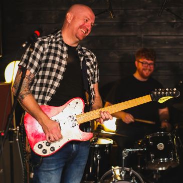 Man smiling while playing electric guitar.