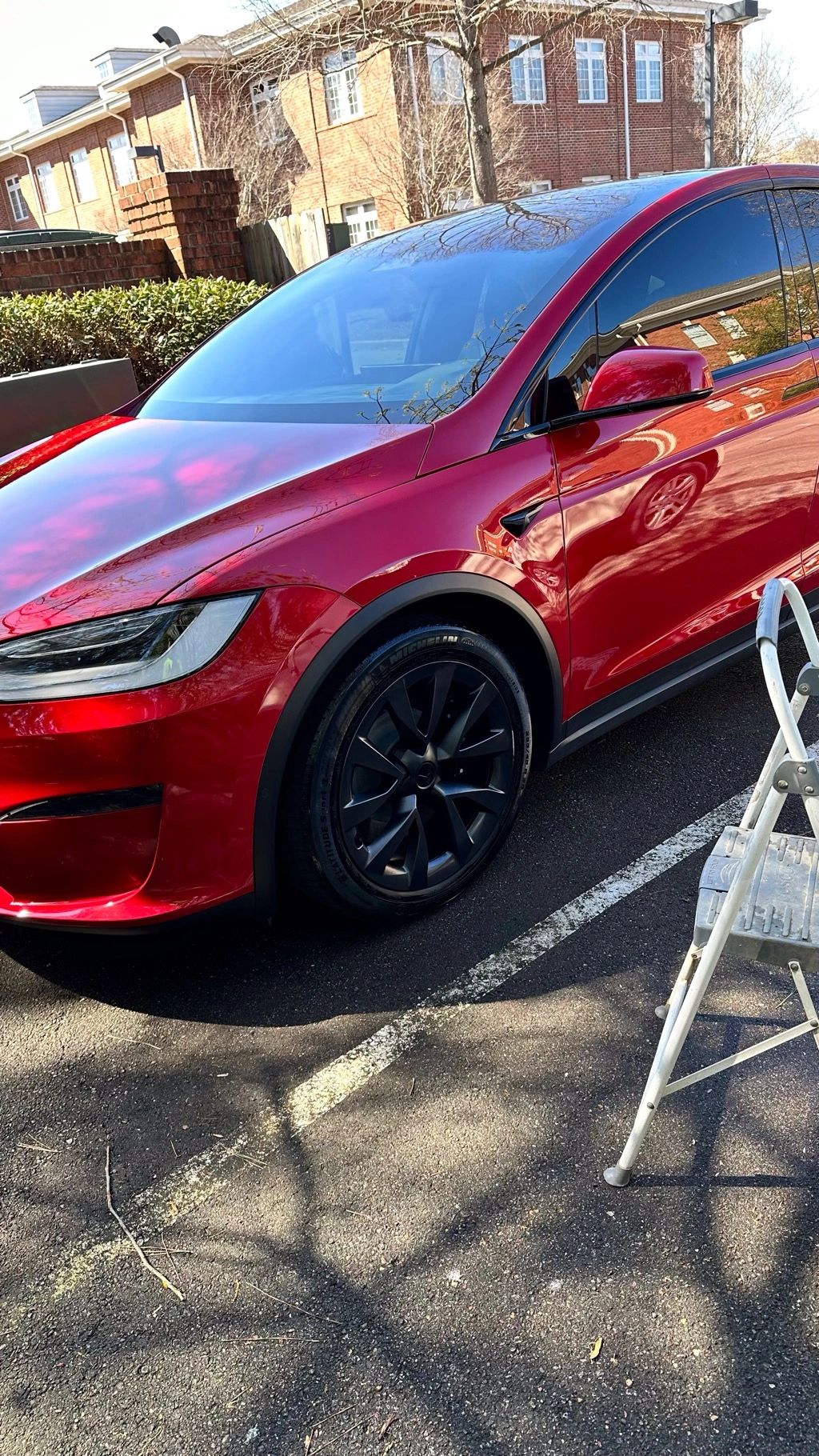 Red Tesla being cleaned in parking lot