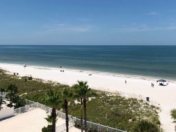 Sunny beach with calm ocean and a few people.