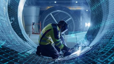 Worker welding inside large industrial pipe with digital schematics overlay.