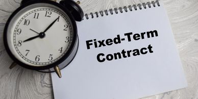 Alarm clock and notebook with 'Fixed-Term Contract' text.