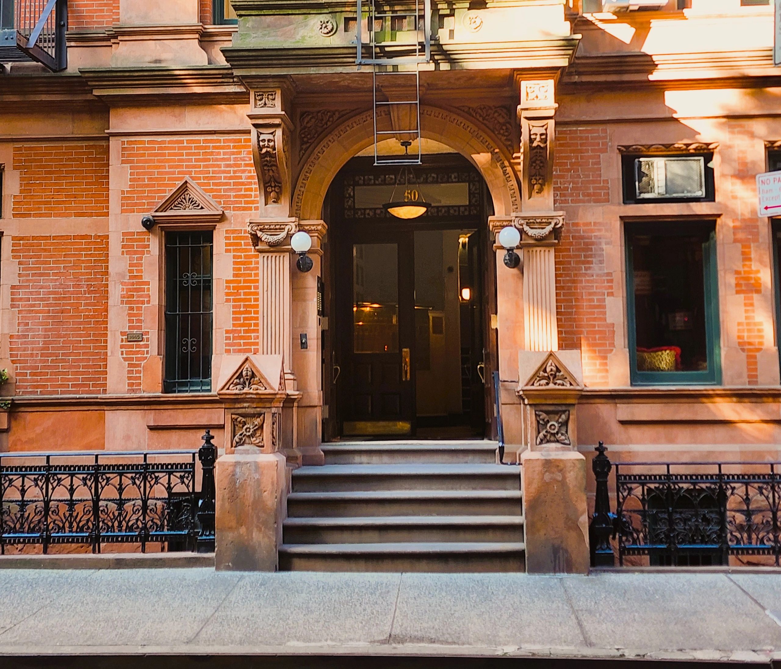 Ornate brownstone building entrance with stone arch and steps.