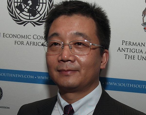 A man in glasses and a suit at a formal event with UN and South South News logos.