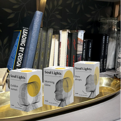 Three Soul Lights boxes displayed on a golden tray with books in the background.