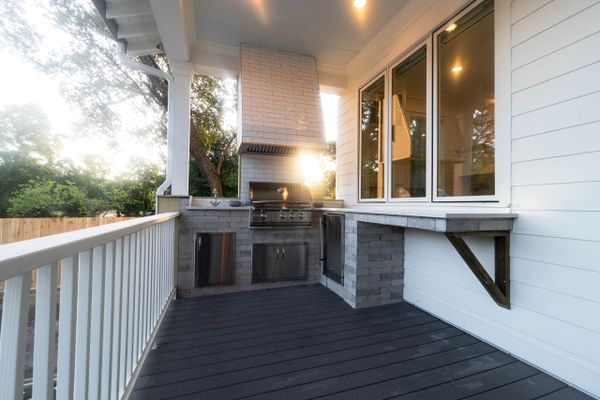 Modern outdoor kitchen with grill and countertop on a spacious deck.