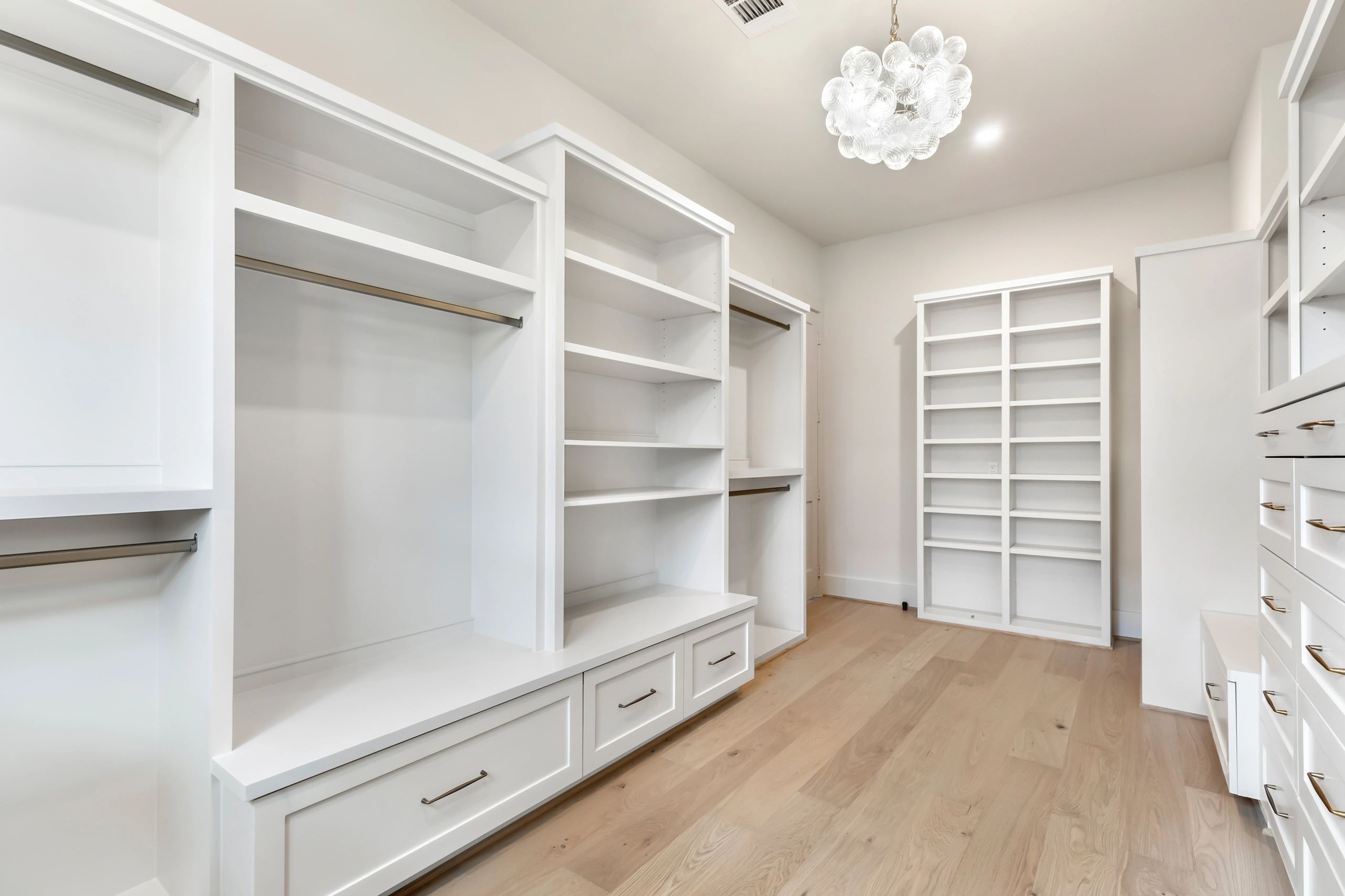 Spacious white walk-in closet with shelves, drawers, and hanging rods.