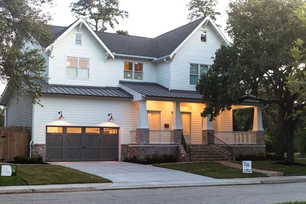 White two-story house with garage and porch lights on at dusk.