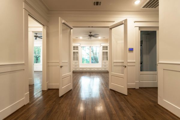 Bright, empty room with open double doors and hardwood floors.