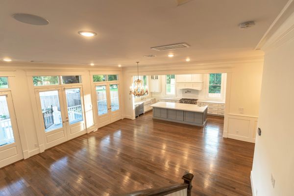 Spacious open kitchen and living area with hardwood floors and large windows.