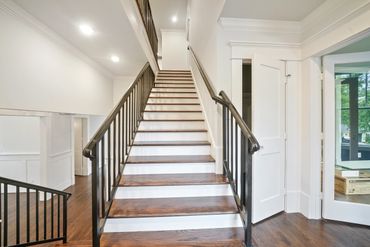 Modern staircase with wooden steps and black iron railings in a bright home.