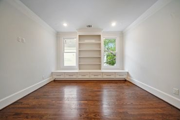 Empty room with built-in shelves and wooden floor.