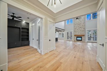 Spacious modern living room with high ceilings and a stone fireplace.