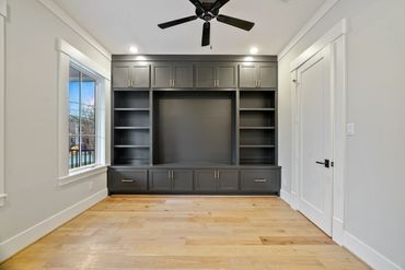 Empty room with built-in black shelving unit and hardwood floor.