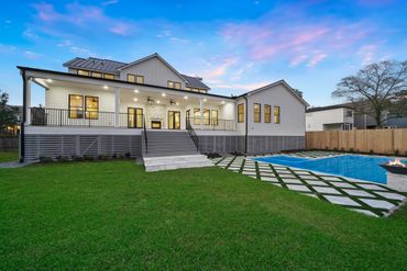 Modern house with spacious backyard and pool at sunset.