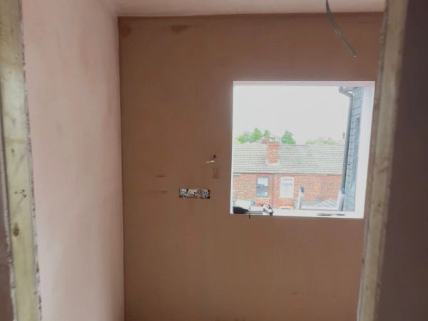 Small room under construction with a window showing houses outside.