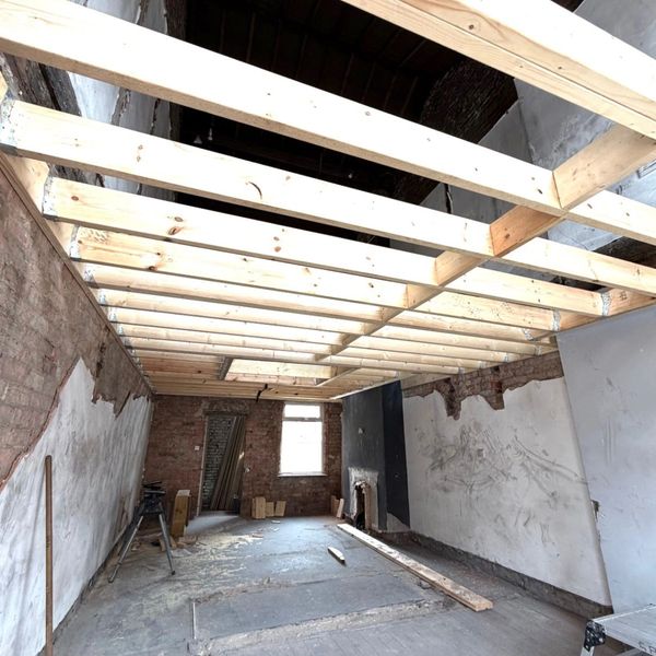 Room under renovation with new wooden ceiling beams installed.