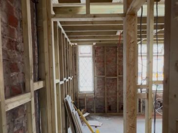 Interior view of a house under construction with exposed wooden framing.