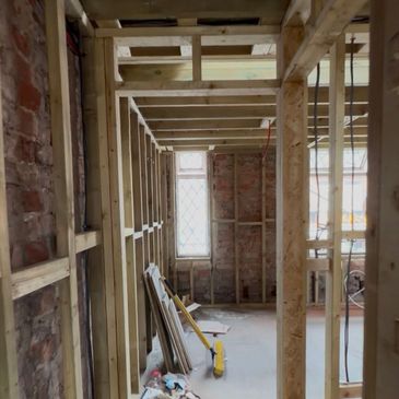 Interior framing of a room under construction with exposed brick walls.