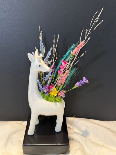 White deer-shaped vase with colorful flowers and branches.
