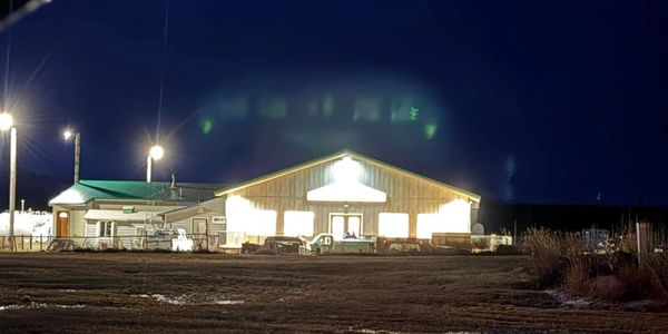 A brightly lit building at night with surrounding vehicles and street lights.