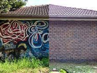 Half wall with graffiti and half plain brick wall under a red-tiled roof.