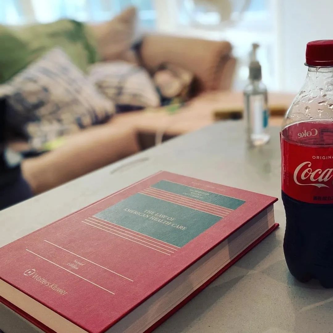Red law book on American healthcare and a Coca-Cola bottle on a table.
