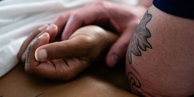 A therapeutic massage therapists applies pressure to a client using his elbow.