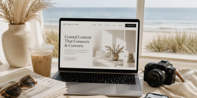 A laptop by the beach displaying a creative studio website, surrounded by stylish accessories.