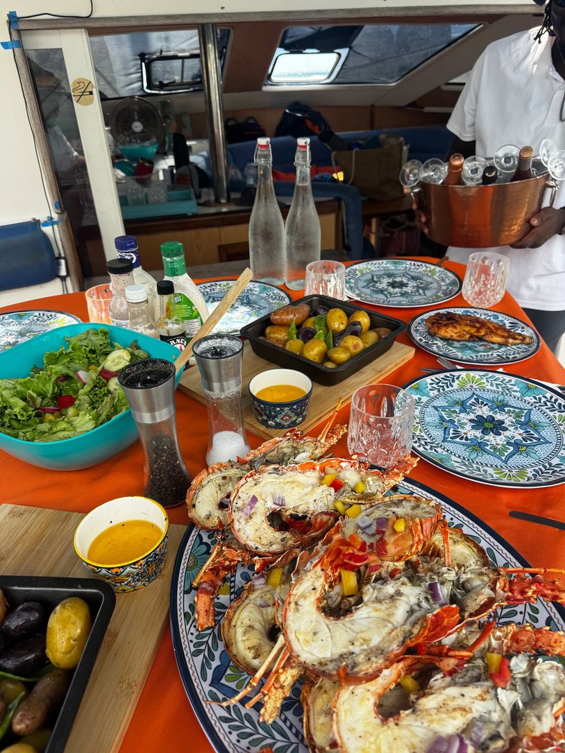 A seafood meal with lobsters, potatoes, and salad on a vibrant table.