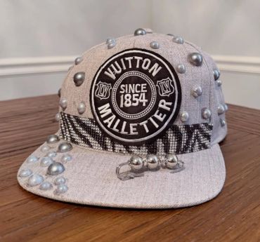 Gray Louis Vuitton Malletier cap with silver studs and decorative patch.