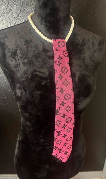 Pearl necklace with a pink designer-patterned fabric tie on a black mannequin.