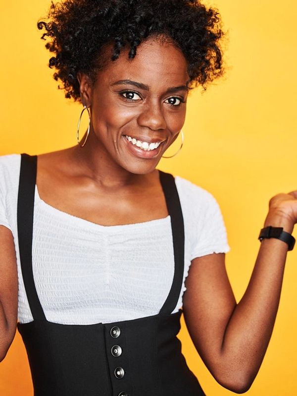 Arlieta Hall smiles wearing a black and white outfit and hoop earrings