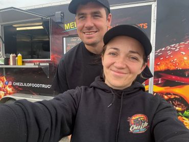 Un couple souriant devant un food truck.