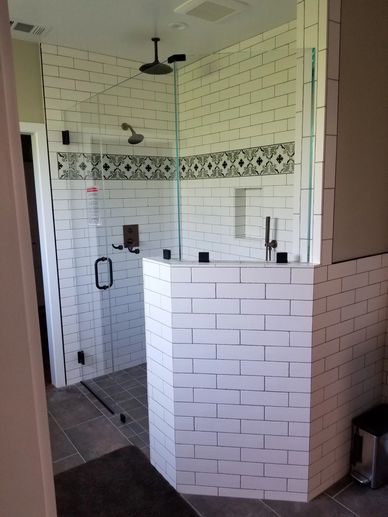 Modern white tiled shower with glass door and decorative accent tiles.
